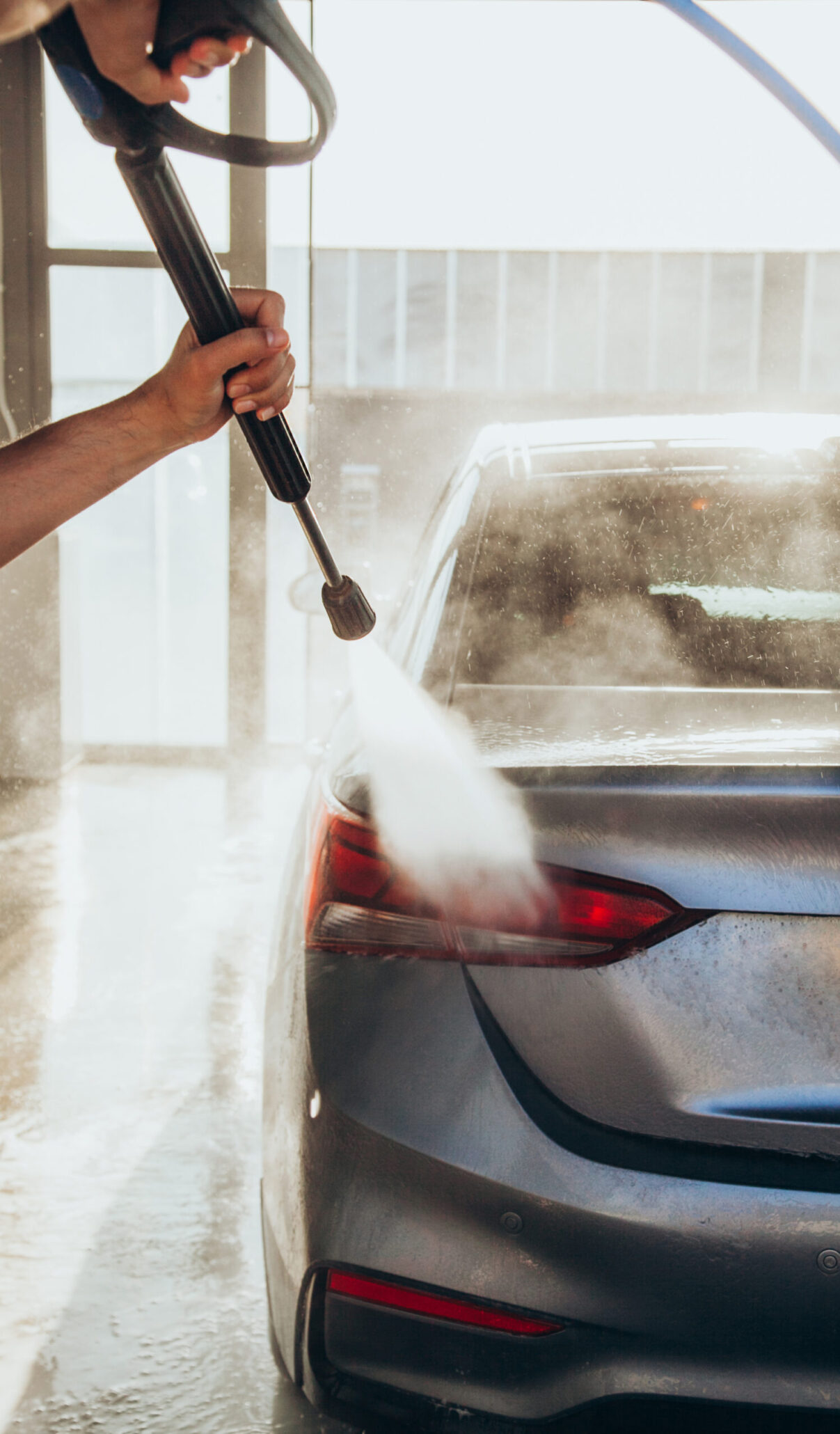 Man pressure washing the back of his vehicle, showcasing thorough cleaning as part of car detailing near me services.