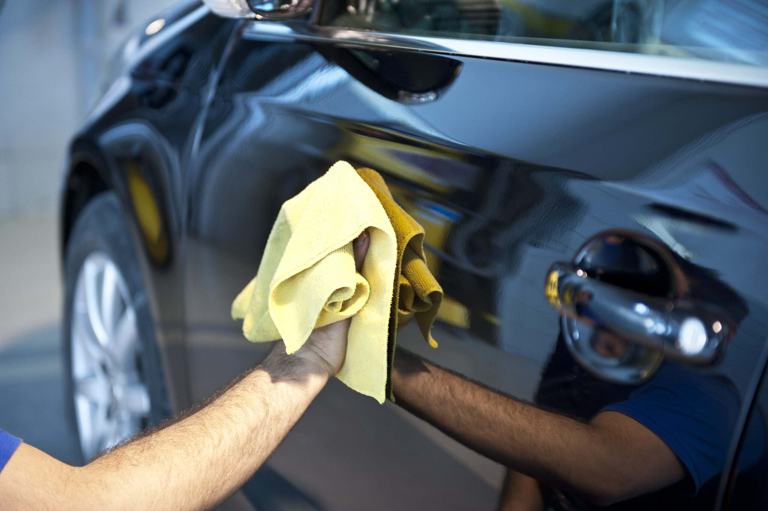 Close-up of a shiny car after paint protection job, being wiped with a microfiber towel