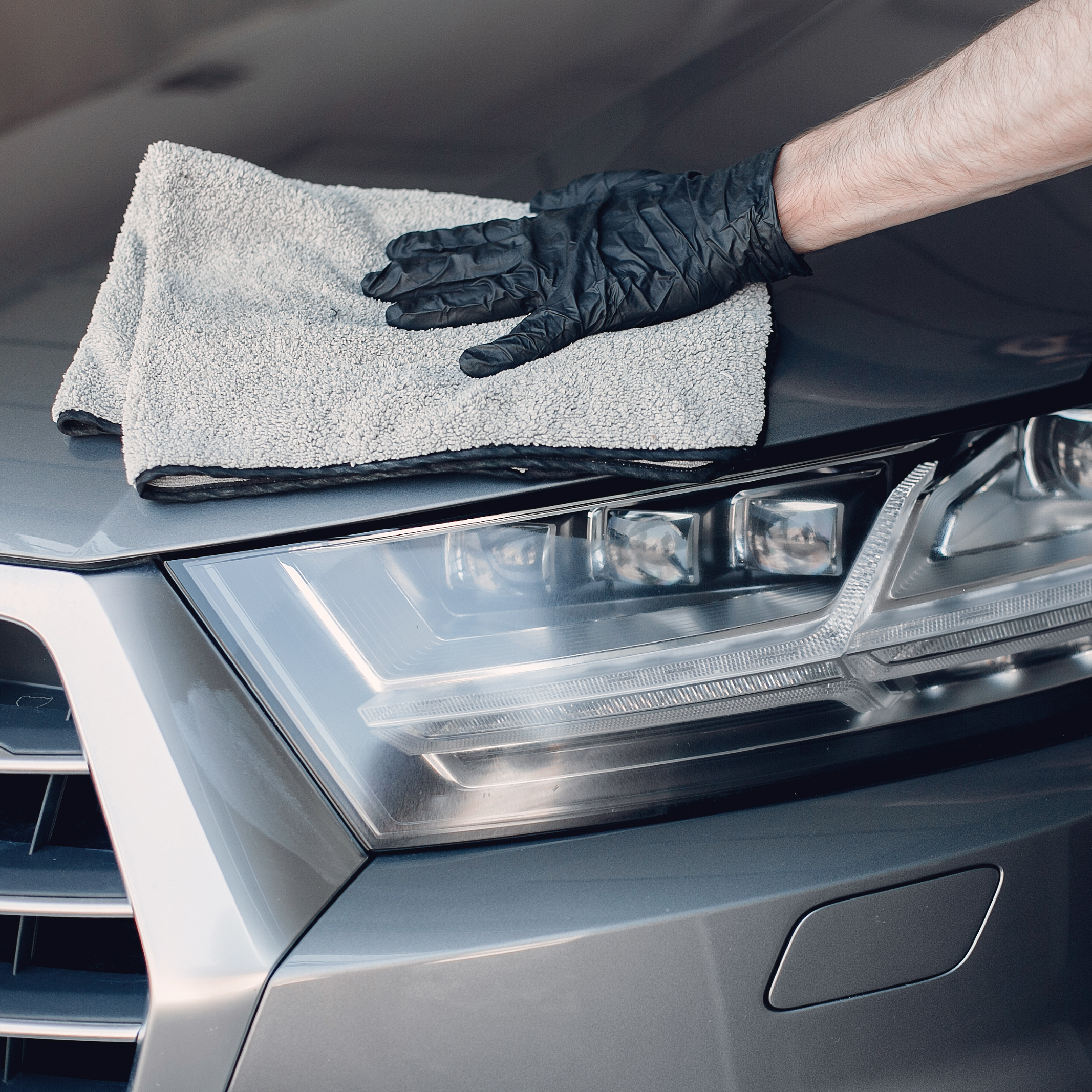 Auto detailer in the RGV carefully wiping off excess residue for a flawless, fully clean vehicle exterior.